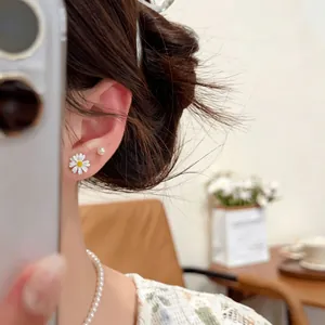 Vista dettagliata di una modella che indossa orecchini a margherita e perle fini