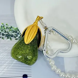 Detailopname van een groene glitterhars peerhanger met parelketting en zilveren hartclip.
