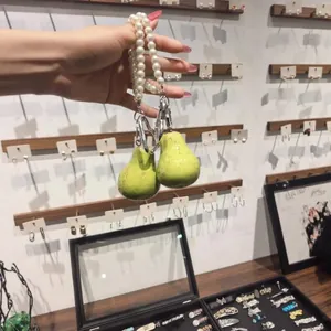Detailweergave van een schattige groene fruit-telefoonketting met witte imitatieparels.