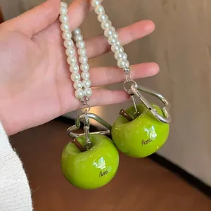 Detailopname van groene hars appelbedels met parels en een hartvormige karabijnhaak.