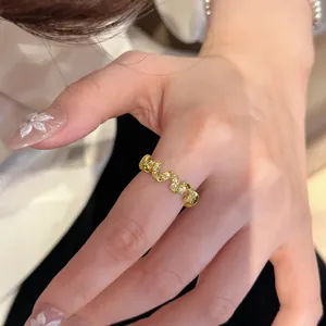 Primo piano di un anello a treccia dorato con cristalli scintillanti al dito