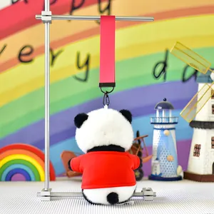 Detailed back view of a cute plush panda keychain wearing a red jacket with pink strap