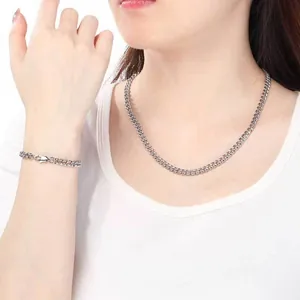 Ensemble collier et bracelet en chaîne cubaine en acier inoxydable poli porté par un modèle