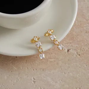 Detail of gold stainless steel ear cuffs with sparkling square cubic zirconia stones.