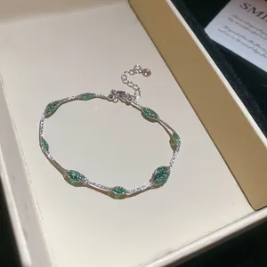 Detailopname van een verzilverde armband met groene gefacetteerde kralen in doosje.