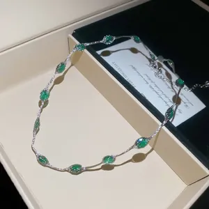 Close-up detail van een minimalistische zilverkleurige ketting met levendige groene ovale stenen