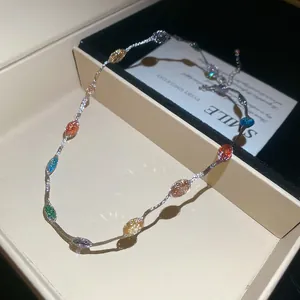 Gedetailleerde weergave van kleurrijke edelsteenketting met zilveren golfketting.