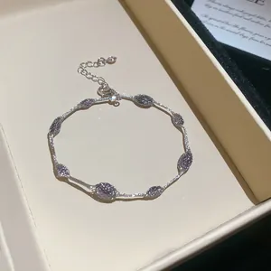 Gedetailleerde macro-opname van een minimalistische zilveren armband met paarse kralen