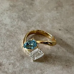Detail des goldenen Toi et Moi Rings mit blauem Tropfen und weißem Smaragdschliff