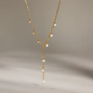 Dettaglio di una collana a Y placcata in oro con eleganti perle e pietre di zirconi