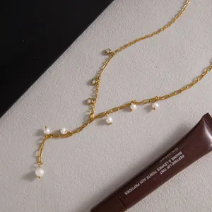 Dettaglio di una collana a Y in acciaio al titanio placcato oro con perle e gemme