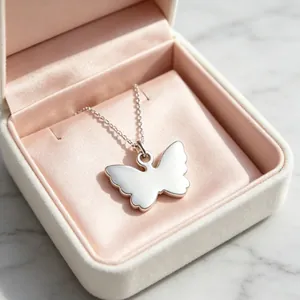 Close-up detail of a mirror-polished butterfly pendant necklace inside a pink gift box