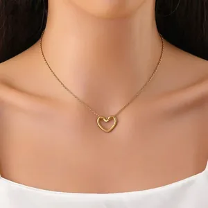 Vista dettagliata di una collana con ciondolo a cuore dorata minimalista sul collo