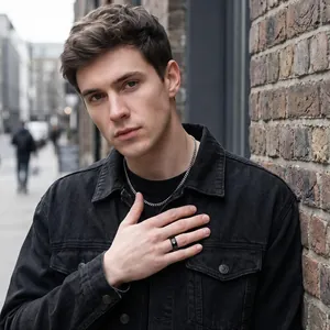 Close-up detail of a male model wearing a black stainless steel spinner ring with a cross