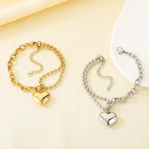 Detailansicht von zweischichtigen Edelstahl-Armbändern in Gold und Silber mit Herzanhänger