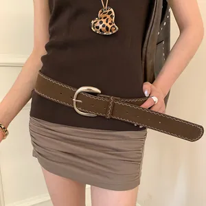 Detail of a wide brown leather belt with white zigzag stitching and a silver oval buckle.