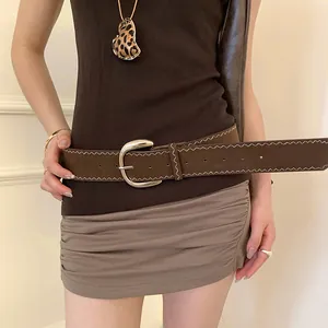 Detail view of a brown Y2K leather belt with white zigzag stitching and silver buckle