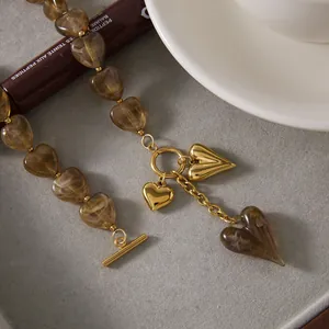 Detailed view of brown acrylic heart beads and gold pendant on stainless steel chain