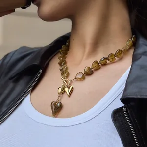 Close-up detail of amber heart acrylic beads necklace with golden OT buckle