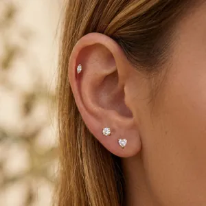 Detailed view of three gold stainless steel ear studs with heart and round crystals