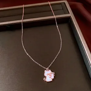 Elegant rose gold cat pendant necklace with shell inlay displayed on a brown tray