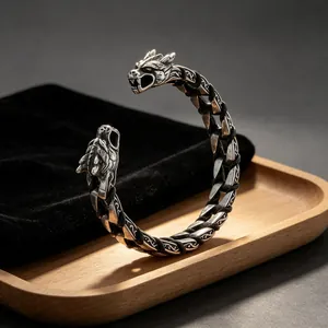 Detailed view of a Viking wolf head bangle with braided leather strap on a wooden tray