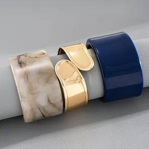 Nahaufnahme von drei professionellen geometrischen Armreifen mit Goldmetall und Marmor