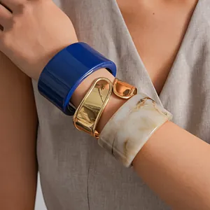 Nahaufnahme von geometrischen Armreifen aus Goldmetall, blauem und Marmor-Harz.