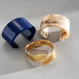 Hochwertiges Set aus Acryl- und goldfarbenen Metall-Armreifen mit modernem Cross-over-Design
