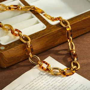 Detail of gold-tone stainless steel chain with amber resin links on a wooden box