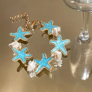 Detailed shot of mint blue starfish bracelet with white pearls on a gold surface