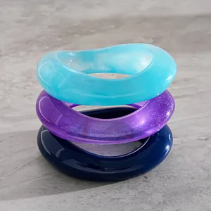 Close-up of three stacked resin bangles in blue and purple with unique wave shapes