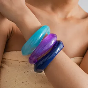 Close-up detail view of three colorful resin chunky bangles worn on a female wrist