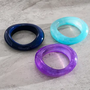 Close-up detail of three chunky resin bangles featuring marbled blue and purple glitter finishes
