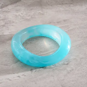 Detail shot of light blue resin marbling oval concave bangle with artistic swirl effect