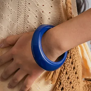 Close-up detail view of a stylish thick blue resin concave bangle worn on a female wrist