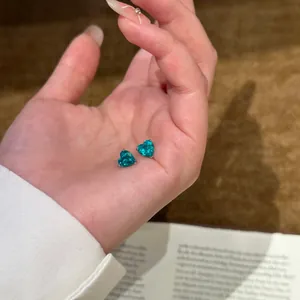 Detaillierte Nahaufnahme von eleganten herzförmigen Ohrsteckern mit türkisfarbenem Zirkonia.