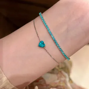 Detailansicht von filigranem Silber-Herzarmband und passendem türkisfarbenem Tennisarmband