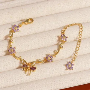Gros plan détaillé d'un bracelet en or avec fleur en zircon violet et nœud élégant