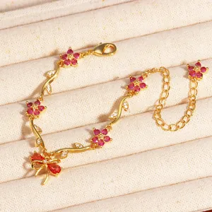 Vue macro détaillée d'un bracelet feuille dorée orné de fleurs en zircon rose et d'un nœud.