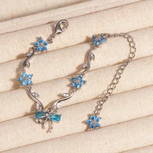 Gros plan d'un bracelet argenté avec fleurs en zircon bleu et motifs de feuilles sur plateau
