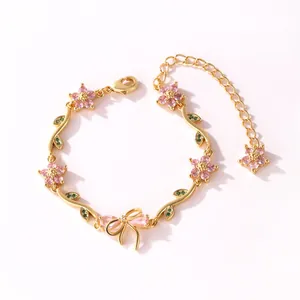 Gros plan détaillé d'un bracelet doré orné de fleurs roses, d'un nœud et de feuilles