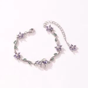 Vue rapprochée d'un bracelet en argent avec des fleurs mauves, des feuilles vertes et un nœud