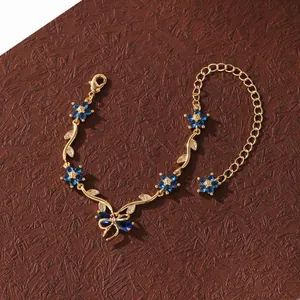 Détail d'un élégant bracelet en or avec fleurs en zircon bleu et motif de nœud papillon