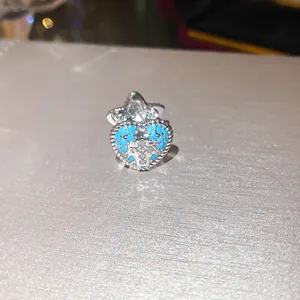 Close-up detail of a heart-shaped ear clip featuring blue stones and a zircon cross design.