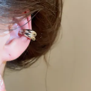 Detailed macro view of a minimalist silver double-band ear cuff shown on a person's ear