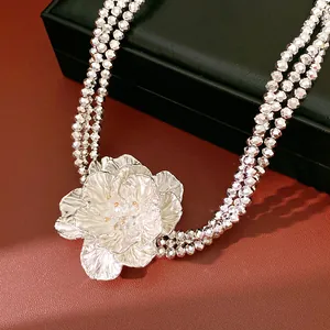 Detailed view of silver faceted beads and layered metal flower pendant necklace