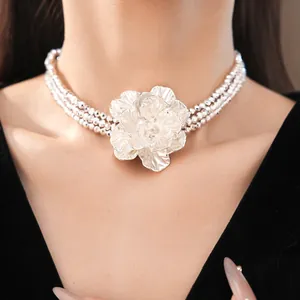 Close-up of a multi-layer beaded necklace with a large silver flower centerpiece