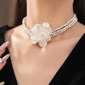 Detail shot of a multi-layer silver beaded choker featuring a large metallic flower pendant.