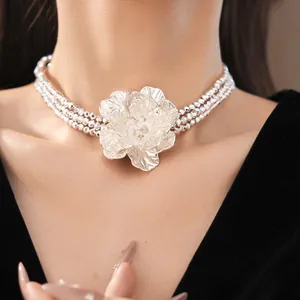 Detail shot of a multi-layer silver beaded choker with a large flower pendant.